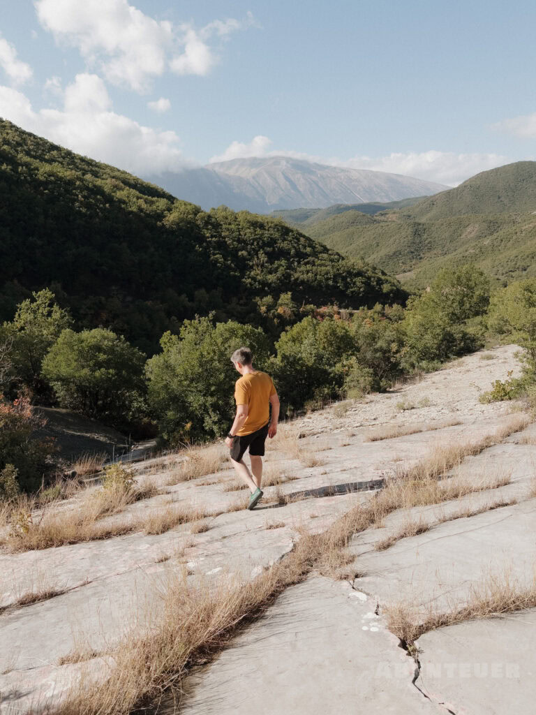 Wanderer in der Natur bei den heißen Quellen, umgeben von Bergen und Wäldern.