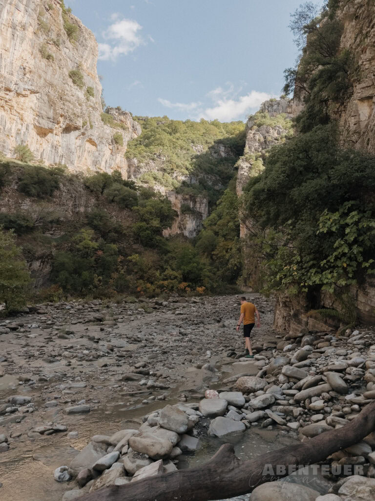 Wanderer bei heißen Quellen in der Natur, umgeben von Felsen und Bäumen.