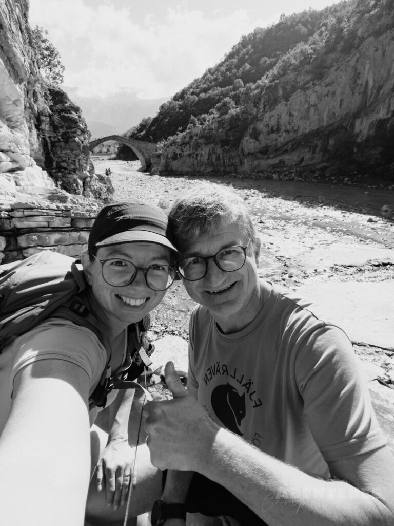 Zwei Camper bei heißen Quellen in der Natur, umgeben von Bergen und Fluss, genießen die entspannende.