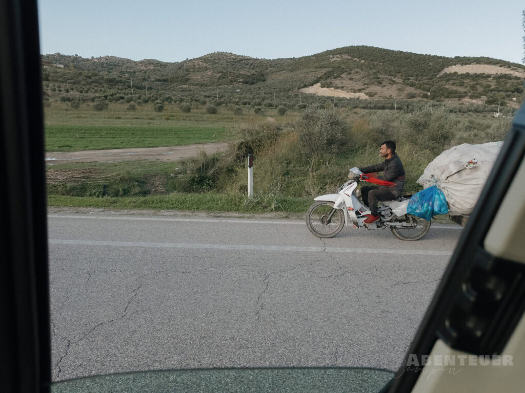 Mann auf Fahrrad mit Gepäck unterwegs in ländlicher Umgebung bei heißen Quellen.